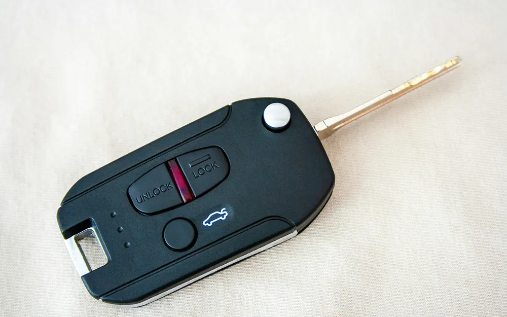 Llave de auto plegable con telemando de botones sobre una superficie clara