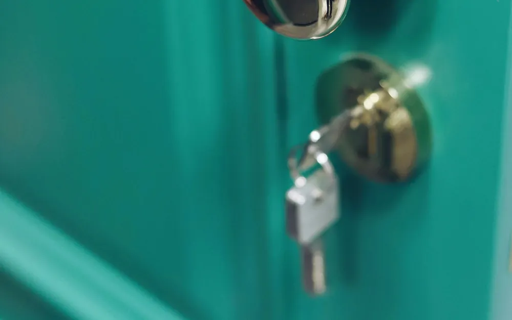 Llave puesta en la chapa de pomo de una puerta verde agua