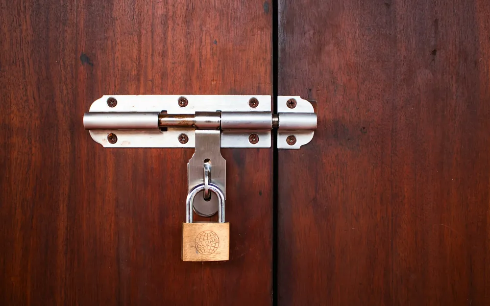 Cerrojo metálico con candado en una puerta de madera