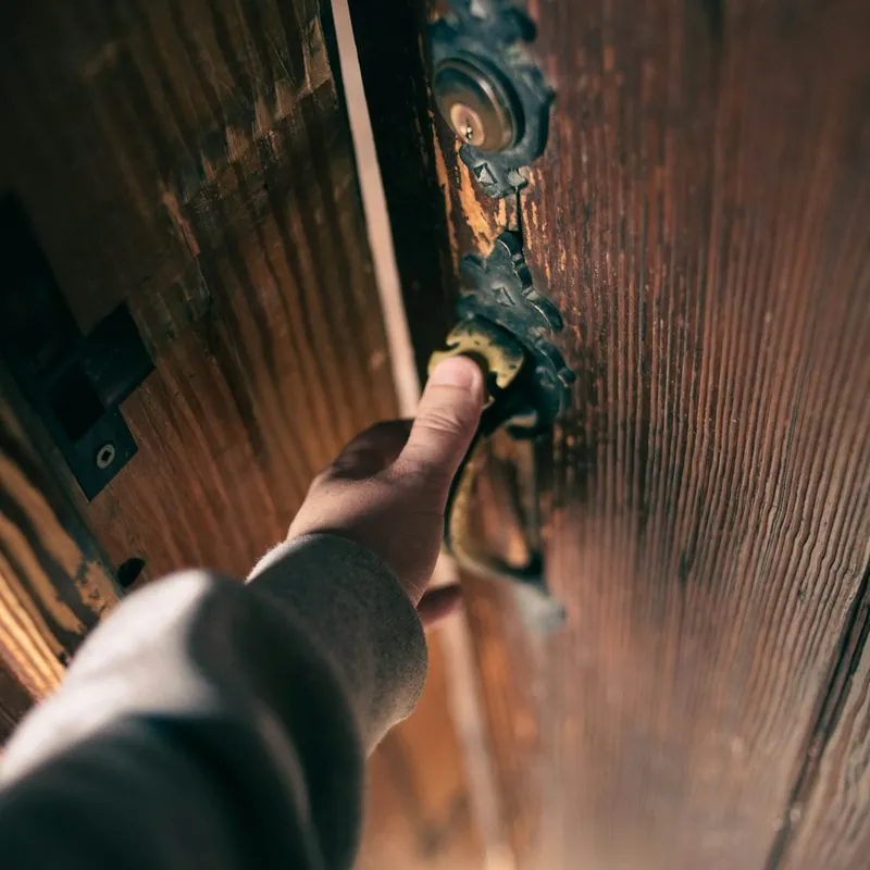 Mano en la manilla de una puerta de madera antigua con llaves en la chapa