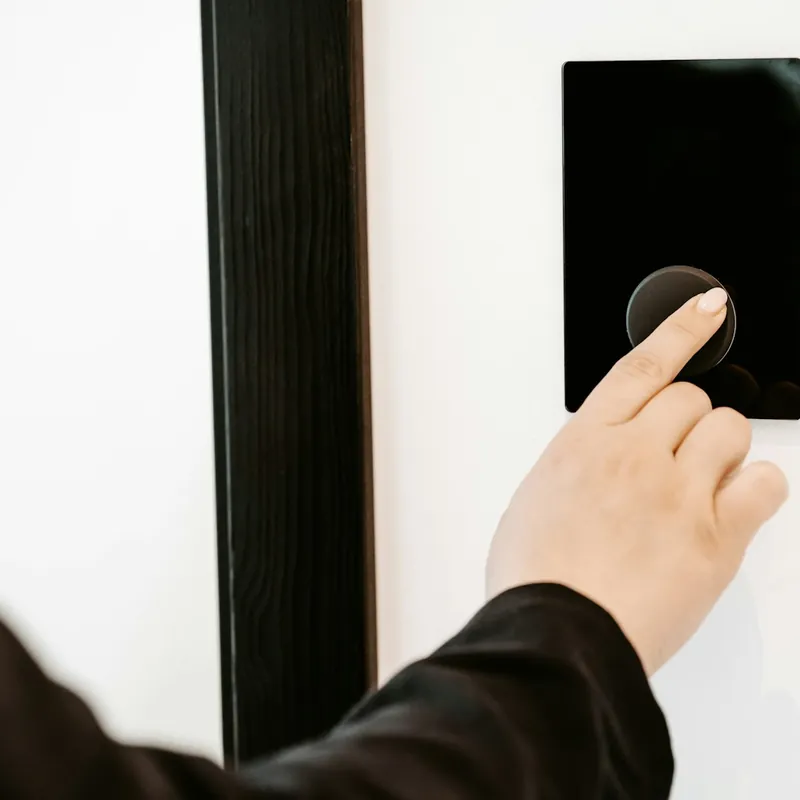 Mano presionando el panel digital de acceso junto a una puerta