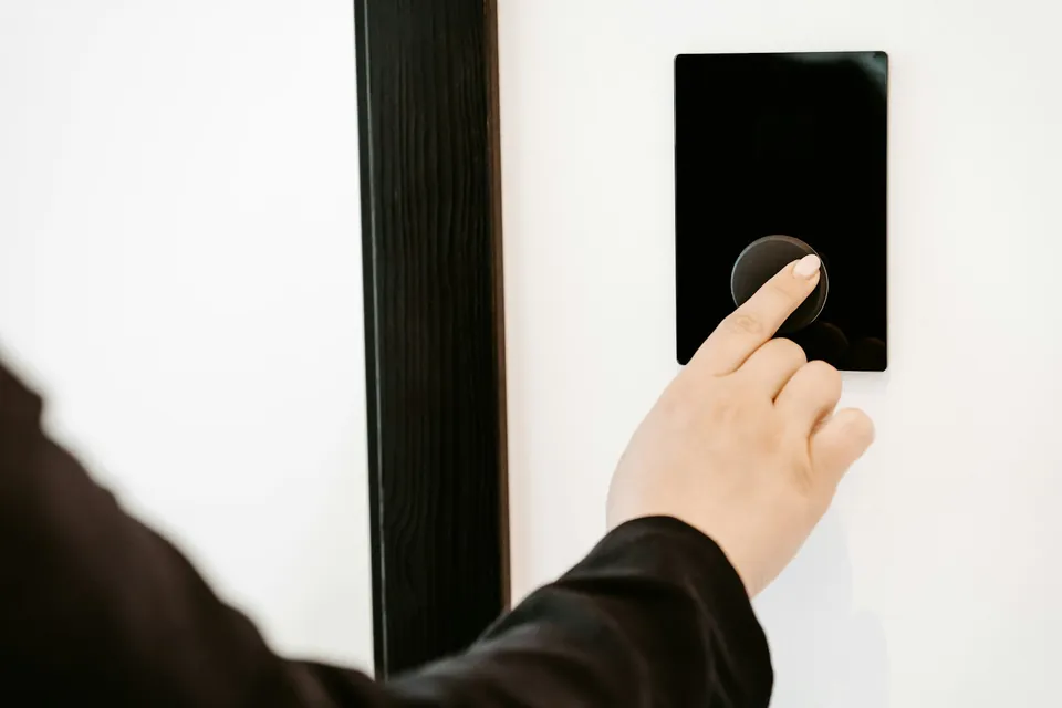 Mano presionando el panel digital de acceso junto a una puerta